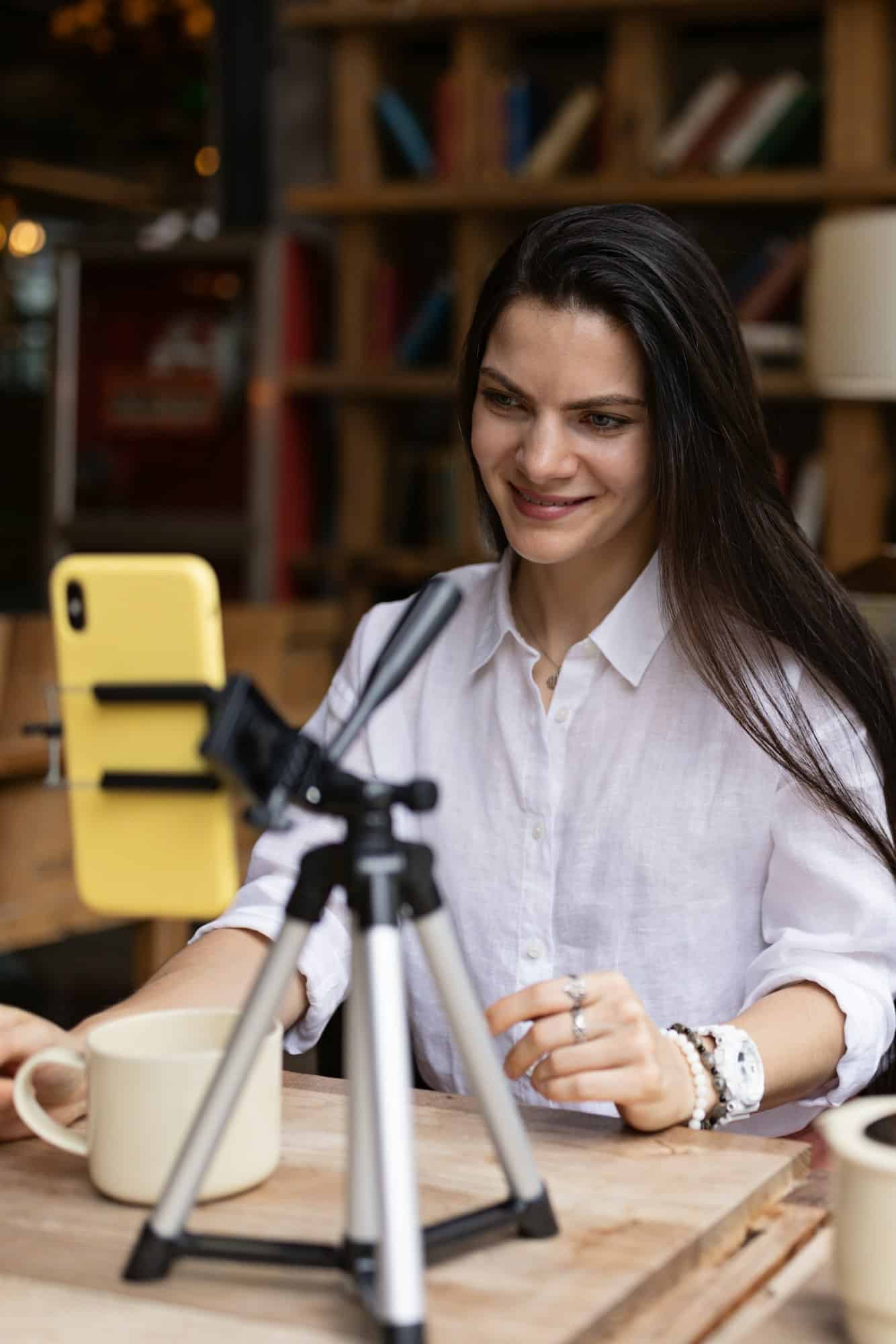 Happy young caucasian woman influencer using technology in cafeteria or studio